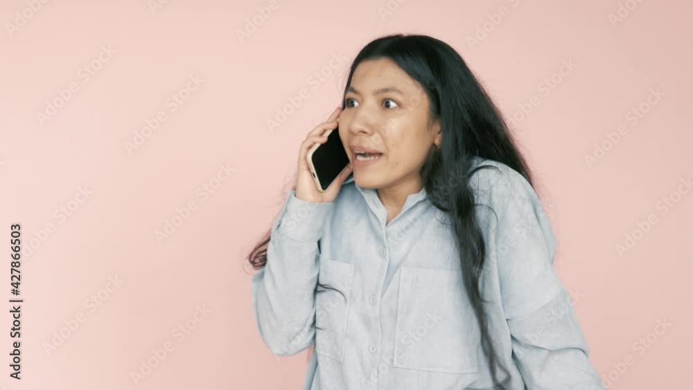 Expressive emotional young pretty hispanic woman having call with friend, using smartphone, talking and emotionally explaining, shouting. Indoor studio shot isolated on pink background Expressive emotional young pretty hispanic woman having call with friend, using smartphone, talking and emotionally explaining, shouting. Indoor studio shot isolated on pink background