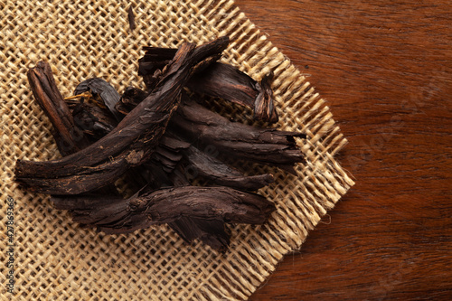 Macro close-up of Organic Alkanna tinctoria or ratan jot on the wooden top background and jute mat. Pile of Indian Aromatic Spice. Top view photo