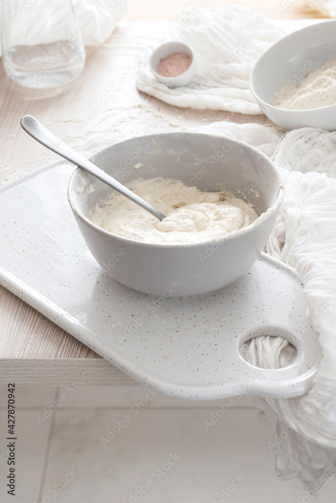 Bowl of dough on a cutting board, and bowl of flour