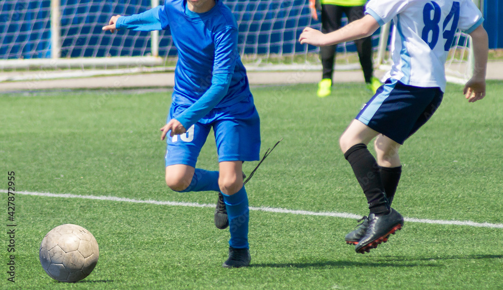 Children's football. An interesting football moment at the match and training. The active struggle and dynamics of the boys' soccer match. The boys are recklessly fighting for the ball