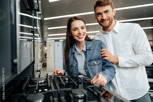 Young couple choosing new gas stove in home appliances store