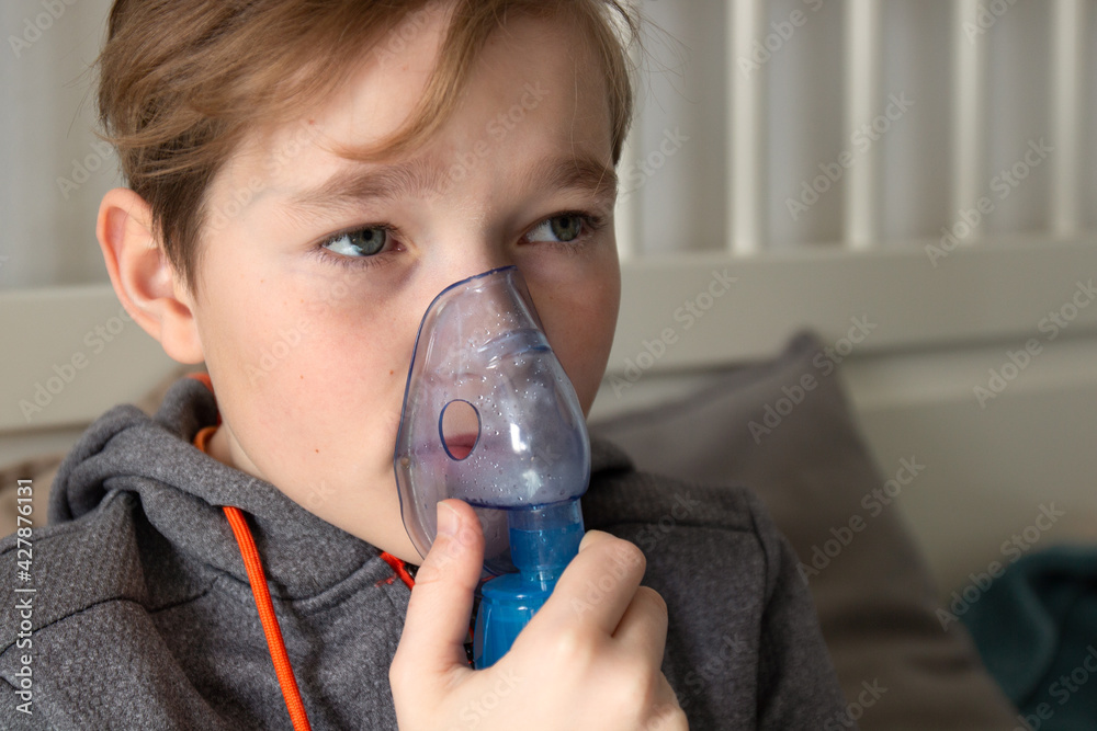 Ten-year-old boy holds nebulizer mask near face. close up