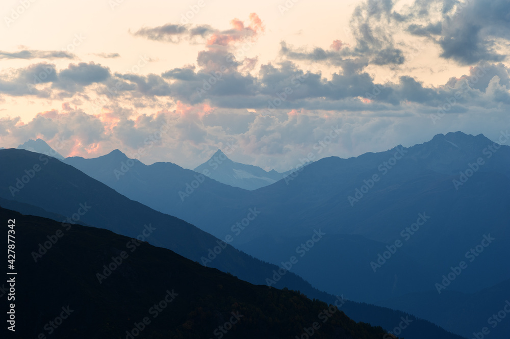 Mountain silhouettes and clouds highlighted by the sun