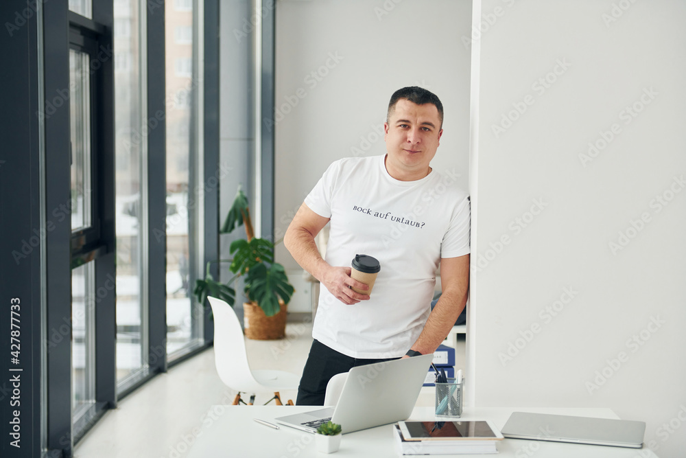 Man standing indoors in the modern office at daytime. Conception of business