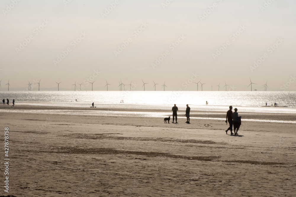 Silhouettes of people walking along a beach
