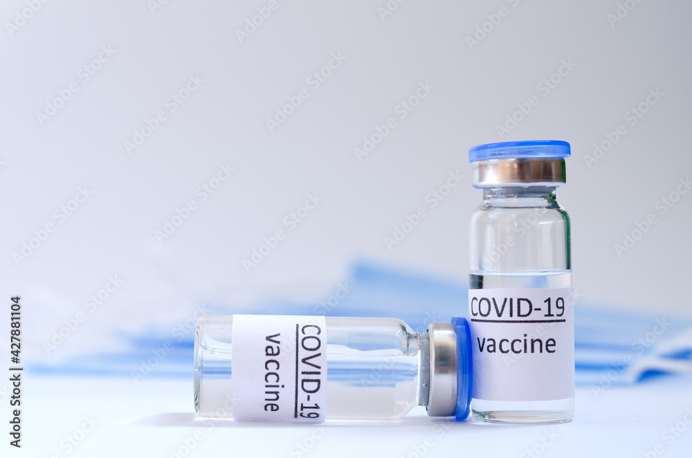 Creative ideas of vaccination concept. Top view of medical masks and vaccine vial glass bottles for vaccination against COVID-19. Coronavirus pandemic. Copy space. Creative ideas of vaccination concept. Top view of medical masks and vaccine vial glass bottles for vaccination against COVID-19. Coronavirus pandemic. Copy space.