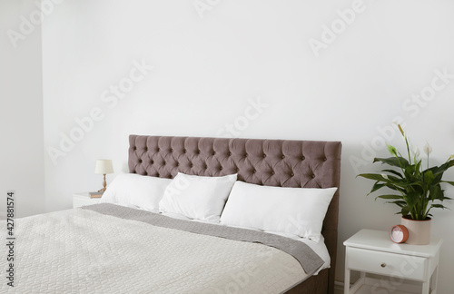 Large bed with blanket and pillows in modern apartment