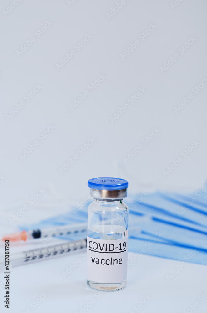 Creative ideas of vaccination concept. Top view of syringe with medical masks and vaccine vial glass bottles for vaccination against COVID-19. Coronavirus pandemic. Copy space. 