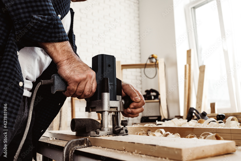 Carpenter cutting wood with electric jigsaw close up