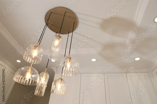 Εκτύπωση καμβά Stylish pendant lamp with light bulbs on ceiling in  modern room