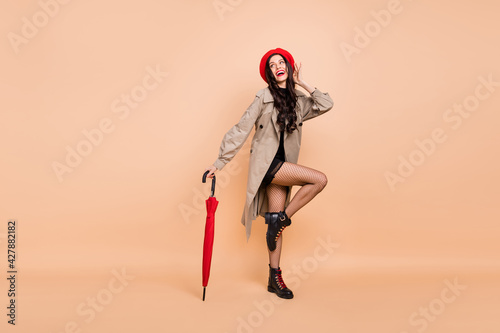 Full length profile side photo of gorgeous lady wear tights look empty space hold umbrella isolated on beige color background