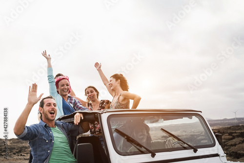 Young people having fun traveling together in convertible 4x4 car during summer vacation - Soft focus on center woman face © DisobeyArt