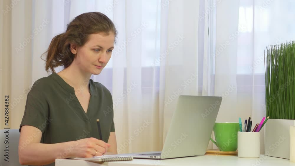 Woman at the computer. Woman takes notes while working with laptop. The student records the lecture. Work at the computer and write documents with a pen. The student is studying online. Woman at the computer. Woman takes notes while working with laptop. The student records the lecture. Work at the computer and write documents with a pen. The student is studying online.