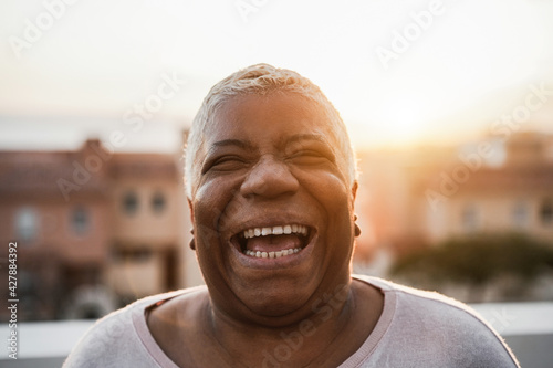 Portrait of happy senior african woman smiling on camera outdoor in the city - Focus on face