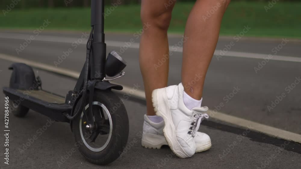 Pan up: Sexy woman posing near electric scooter Pan up: Sexy woman posing near electric scooter