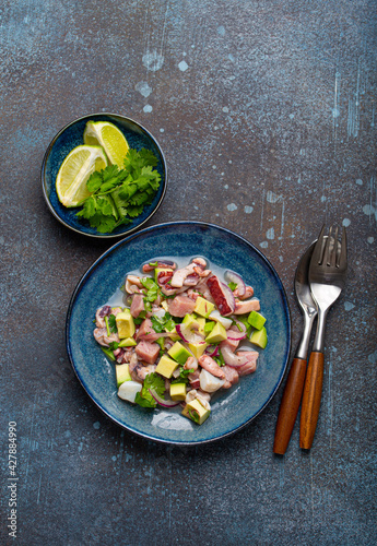 Peruvian ceviche with fresh fish, seafood, avocado on ceramic blue plate on rustic stone background from above, traditional dish of Peru cuisine  photo