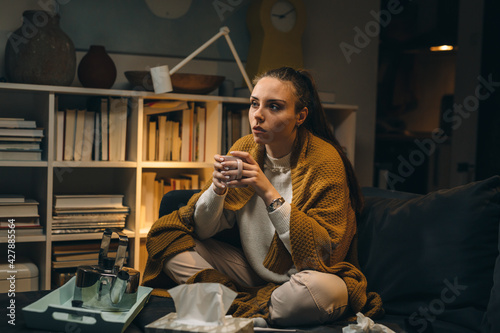 woman has coronavirus. she is sitting at home drinking tea