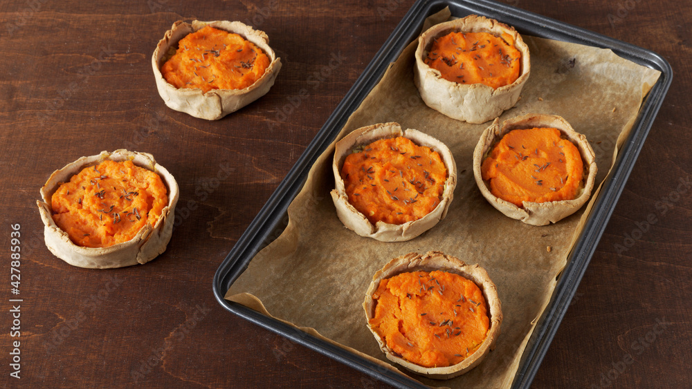 Carrot pies top view in a tray. Pastry with carrot and potato filling with caraway seeds. Rye flour homemade pastry. Carrot pies top view in a tray. Pastry with carrot and potato filling with caraway seeds. Rye flour homemade pastry.