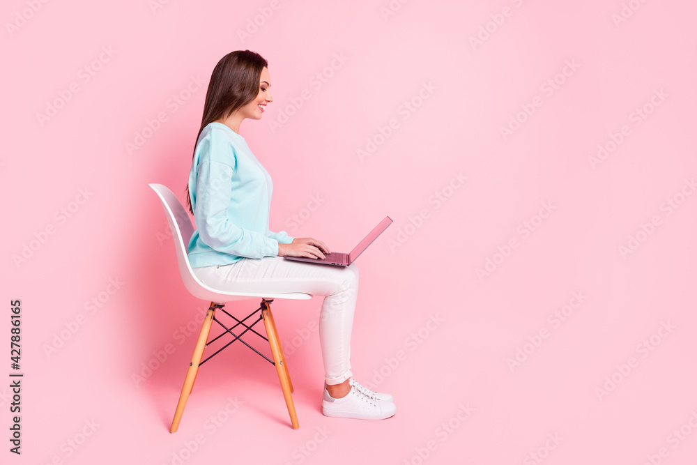 Full length profile portrait of attractive person use laptop good mood wear sweater isolated on pink color background Full length profile portrait of attractive person use laptop good mood wear sweater isolated on pink color background