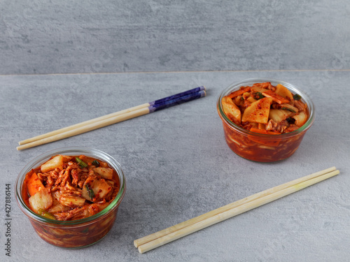 Two portions of kimchi in glass bowls with chopsticks. Korean traditional fermented food.