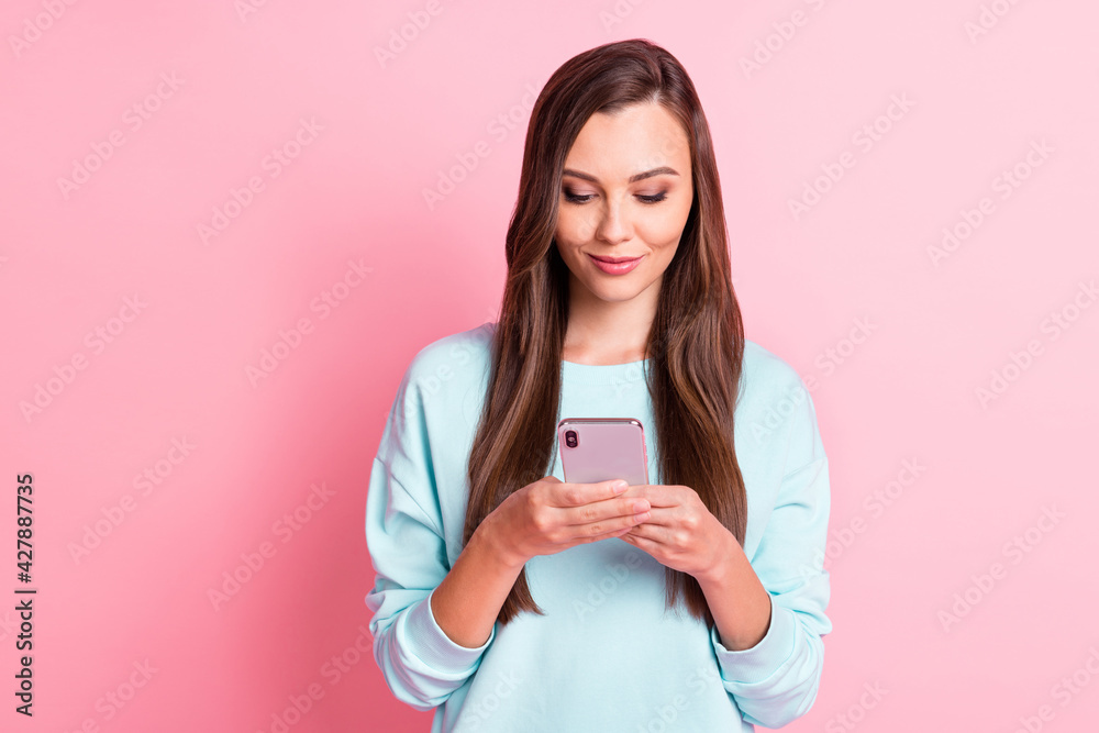 Photo of serious brown haired young woman hold smartphone texting media isolated on shine pink color background Photo of serious brown haired young woman hold smartphone texting media isolated on shine pink color background