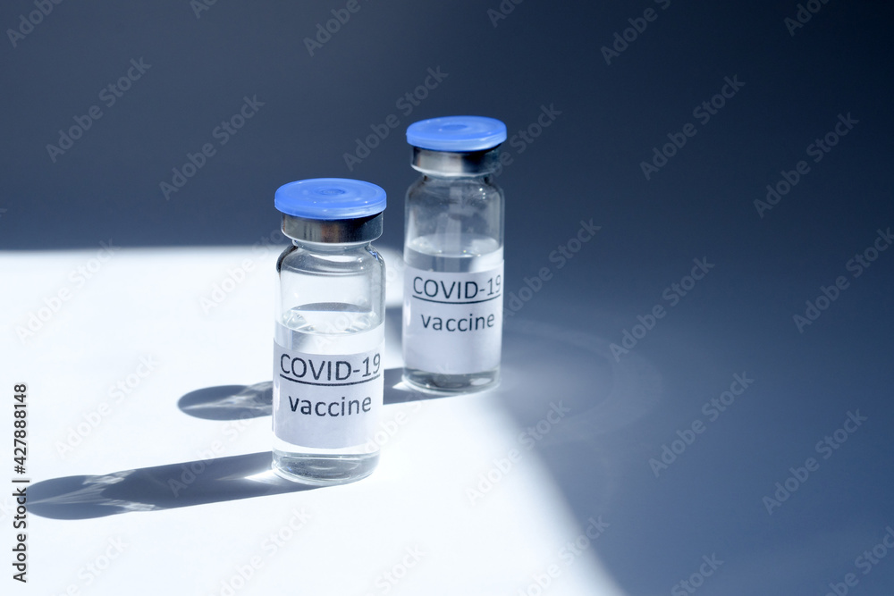 Creative ideas of vaccination concept. Top view of medical masks and vaccine vial glass bottles for vaccination against COVID-19. Coronavirus pandemic. Copy space. 