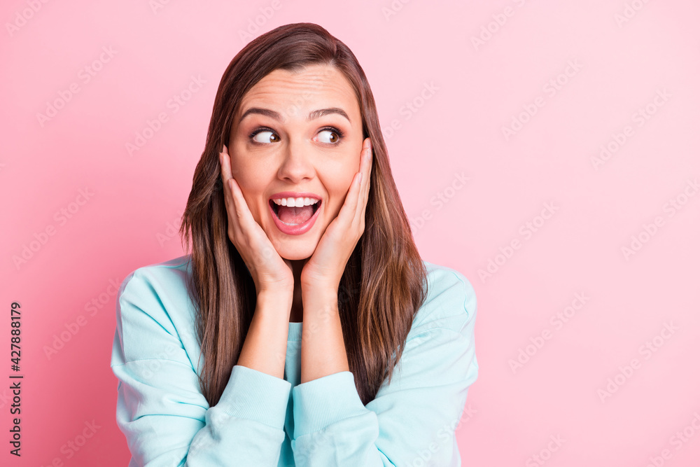 Photo of amazed pretty woman look empty space hold hands cheeks isolated on pastel shine pink color background Photo of amazed pretty woman look empty space hold hands cheeks isolated on pastel shine pink color background