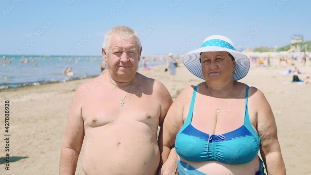 Happy senior couple hugging on summer beach. Elderly couple rest at tropical beach. Senior Couple Enjoying Beach Holiday. Family, tourism and people concept. Happy senior couple hugging on summer beach. Elderly couple rest at tropical beach. Senior Couple Enjoying Beach Holiday. Family, tourism and people concept.