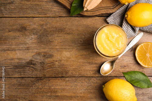 Delicious lemon curd and fresh fruits on wooden table, flat lay. Space for text