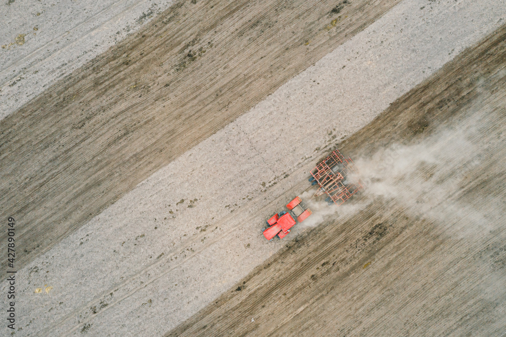 Spring plowing field red tractor aerial photography with drone. Agricultural work in the field in spring. Planting potatoes, beets and other crops. Spring plowing field red tractor aerial photography with drone. Agricultural work in the field in spring. Planting potatoes, beets and other crops.