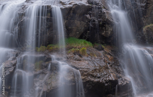 waterfall with silk effect water and wet stones and green grassy areas