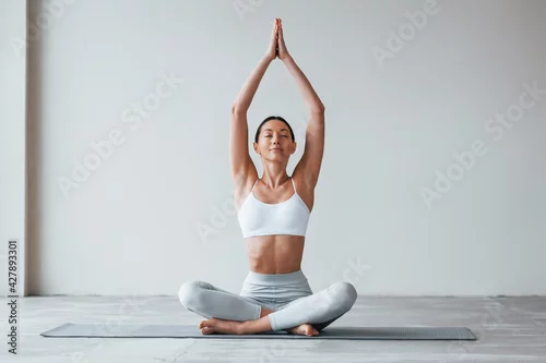 Obraz Sits on yoga mat. Woman with sportive slim body type in underwear that is in the studio