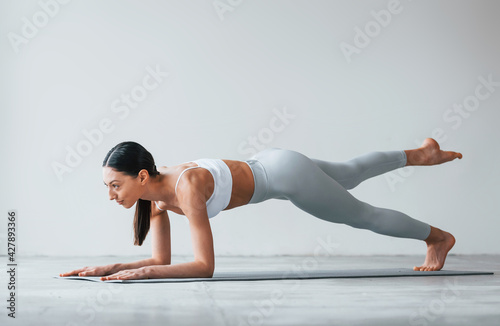 Doing yoga exercises. Woman with sportive slim body type in underwear that is in the studio photo