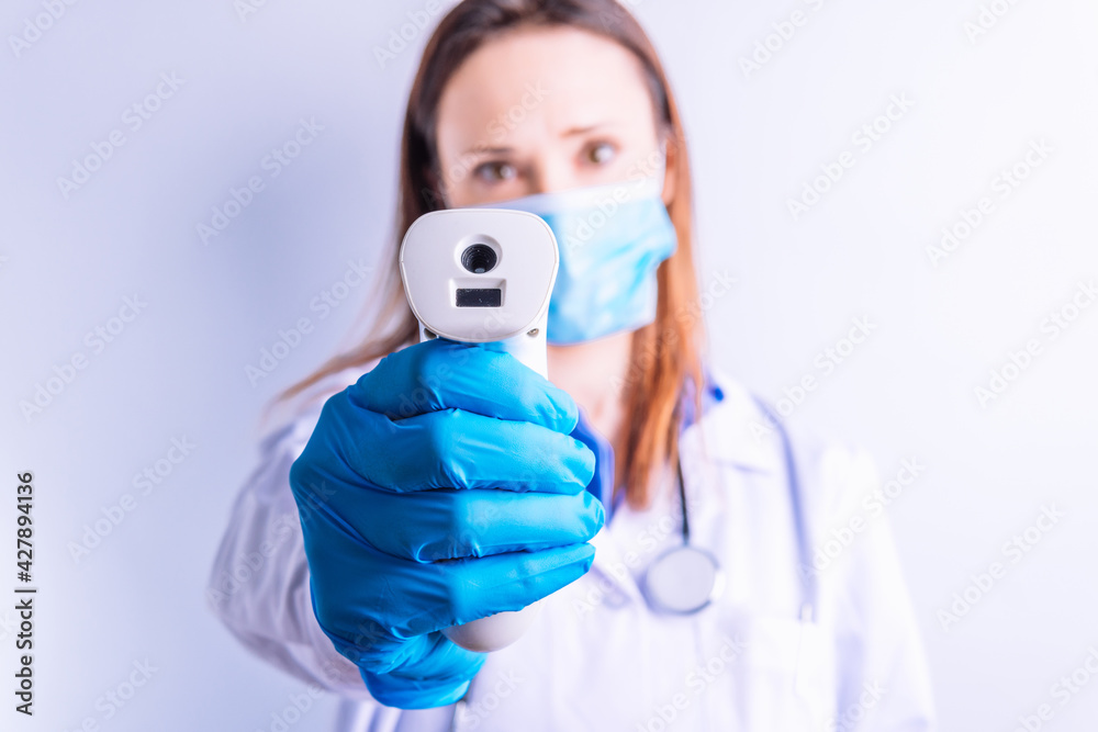 Defocused doctor holding a laser thermometer in front medicine concept Defocused doctor holding a laser thermometer in front medicine concept