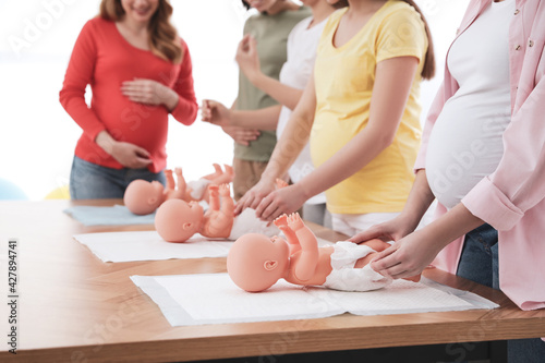 Tableau sur toile Pregnant women learning how to swaddle baby at courses for expectant mothers ind