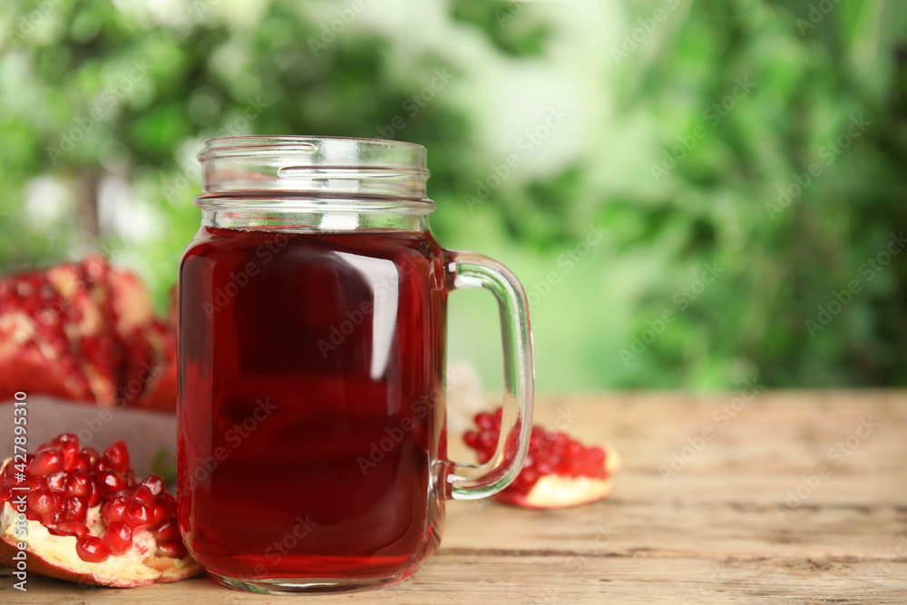 Pomegranate juice in mason jar and fresh fruits on wooden table outdoors, space for text Pomegranate juice in mason jar and fresh fruits on wooden table outdoors, space for text
