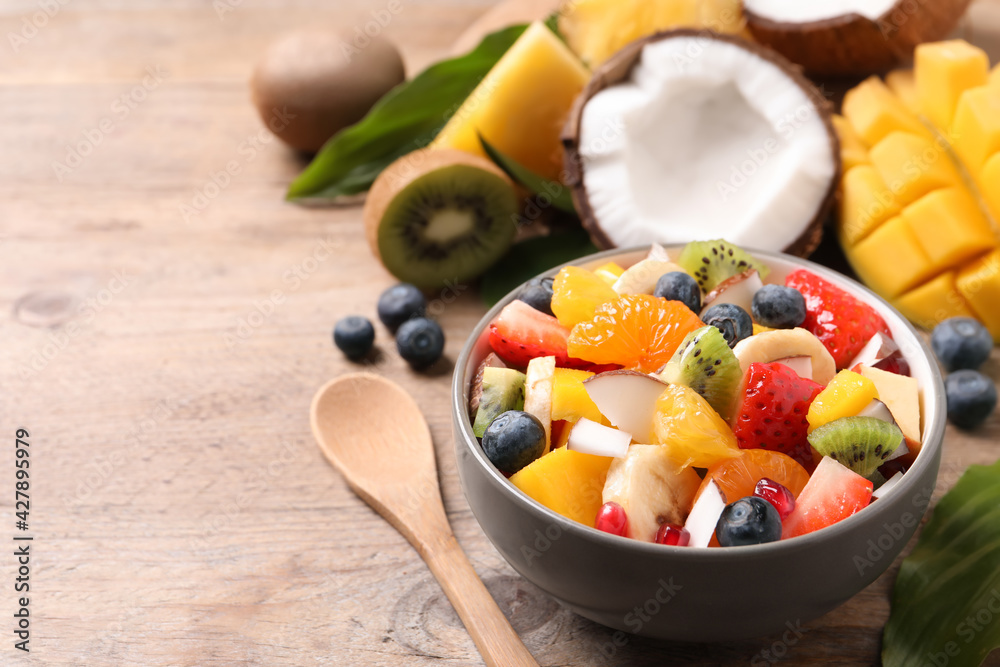 Bowl of delicious fruit salad on wooden table, space for text Bowl of delicious fruit salad on wooden table, space for text