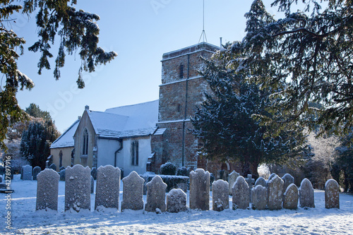 An old church and row of gravestones in the snow