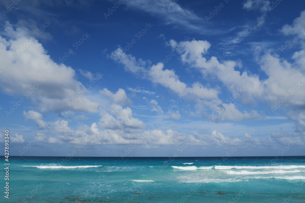 Ocean horizon idyllic scene, blue sky with some fluffy white clouds and turquoise water arranging a relaxed atmosphere, perfect wallpaper to dream
