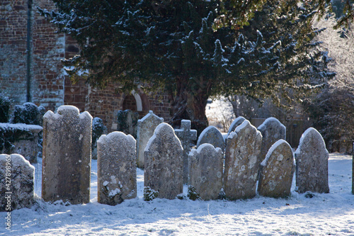 Obraz na plátne a row of old gravestones covered in snow in a churchyard