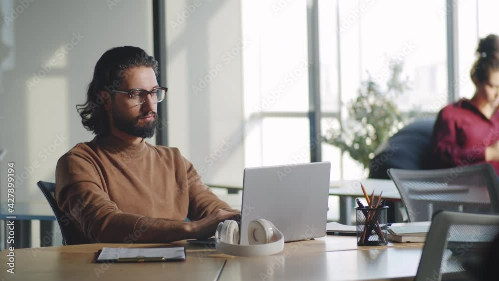 Handsome middle eastern businessman working on laptop at desk in open space office Handsome middle eastern businessman working on laptop at desk in open space office