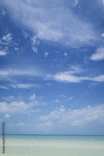 Ocean horizon idyllic scene, blue sky with some fluffy white clouds and turquoise water arranging a relaxed atmosphere, perfect wallpaper to dream