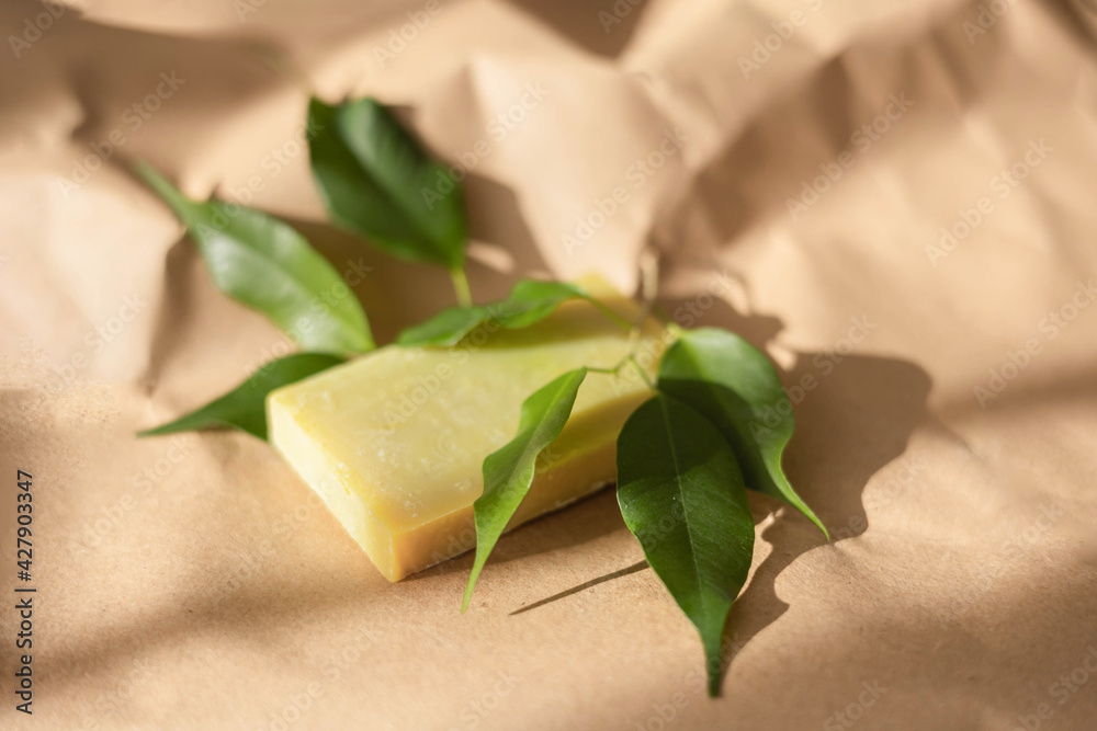 Handmade soap bar and green leaves on paper background with shadow. Concept of natural organic spa cosmetics. Herbal products. Top view, flat lay Handmade soap bar and green leaves on paper background with shadow. Concept of natural organic spa cosmetics. Herbal products. Top view, flat lay