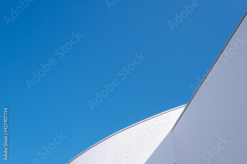 part of modern shaped white roof against blue sky