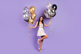 Full length photo of attractive stunning young woman hold balloons good mood isolated on violet color background