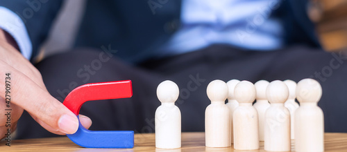 Bild auf Leinwand Businessman hand holding magnet and pulling man wooden figure from the crowd employee