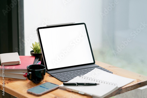 Blank screen tablet with keyboard on wooden table in coffee shop.