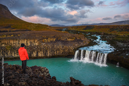 Hiker standing at the edge of the Thjofafoss waterfall in Iceland photo