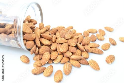 Almonds pour from bottle, isolated on white background