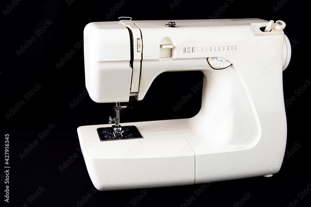 White automatic sewing machine on black background.